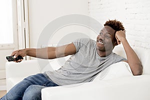 Attractive black african american man sitting at home sofa couch watching television