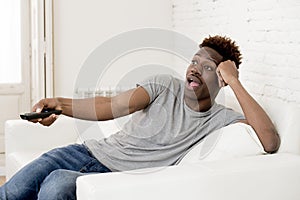 Attractive black african american man sitting at home sofa couch watching television