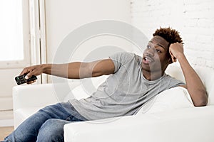 Attractive black african american man sitting at home sofa couch watching television