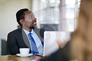 Attractive black businessman sitting and concentrated listening to presentation in a multiracial business meeting