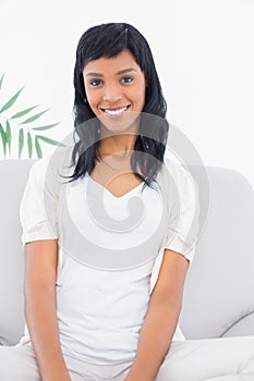 Attractive black haired woman in white clothes posing looking at camera