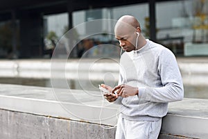 Attractive black man listening to music with headphones in urban