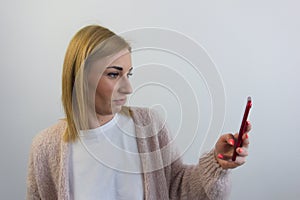Attractive blond caucasian woman reading text message or browsing the net on her mobile phone