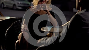 Attractive blond female seducing man on restaurant terrace, escort service