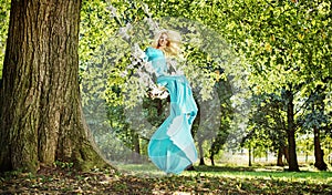 Attractive blond lady on a flower seesaw in a park