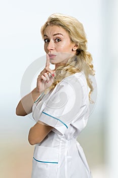 Attractive blond nurse gesturing silence.