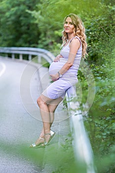 Attractive blond pregnant woman on forest background