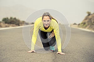 Attractive blond sport woman ready to start running practice training race starting on asphalt road mountain landscape