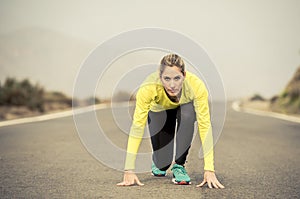 Attractive blond sport woman ready to start running practice training race starting on asphalt road mountain landscape