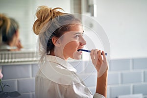 Attractive blond woman brushing teeth