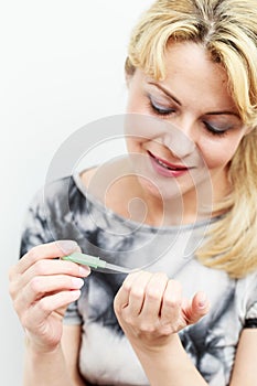 Attractive woman filing her fingernails