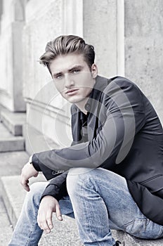 Attractive blond young man sitting outdoors