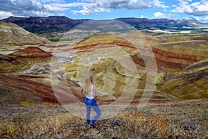 Attractive blond young woman is impressed by the view of the Painted Hills Unit - John Day Fossil Beds National Monument, Oregon,