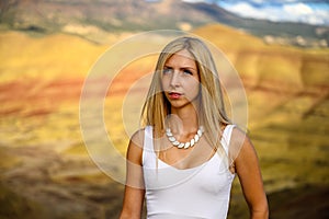 Attractive blond young woman is impressed by the view of the Painted Hills Unit - John Day Fossil Beds National Monument, Oregon,