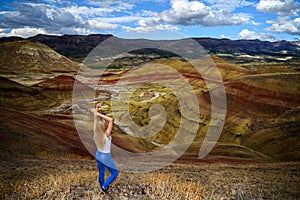 Attractive blond young woman is impressed by the view of the Painted Hills Unit - John Day Fossil Beds National Monument, Oregon,