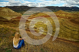 Attractive blond young woman is impressed by the view of the Painted Hills Unit - John Day Fossil Beds National Monument, Oregon,