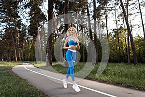 Attractive blonde caucasian woman with sexy body in fashion sports blue clothes enjoy run in park in sunny day. Girl running among