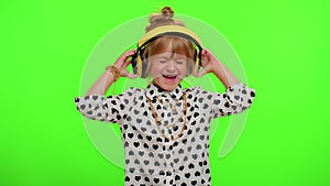 Attractive blonde child kid listening music via headphones dancing disco fooling having fun party