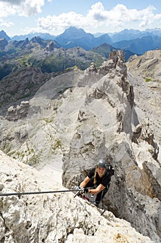 Attractive blonde female climber on a steep Via Ferrata in the Italian Dolomites