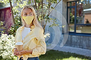 Attractive blonde female in medical mask looks away photo