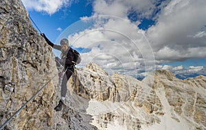 Attractive blonde female mountain climber on a steep Via Ferrata in the Italian Dolomites