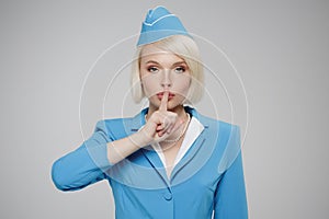 Attractive blonde flight attendant encourages silence. photo