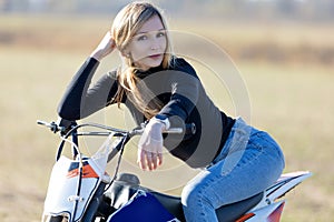 Attractive blonde girl on motocross. Sporty woman biker at motobike.