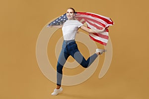 Attractive blonde made a jump with an American flag. photo shoot in the studio on a yellow background