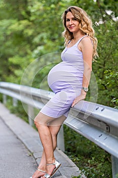 Attractive blonde pregnant woman on forest background