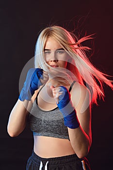 Attractive blonde sportswoman in kickboxing bandages in defensive stance