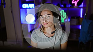 Attractive blonde streamer immerses in riveting game, streaming live from gaming room, lighting up the night with digital