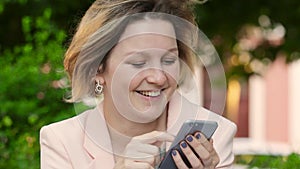 Attractive blonde white woman working freelance and using smartphone in park at sunny day