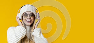 Attractive blonde woman listening to music over yellow background
