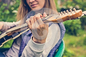 Attractive blonde woman playing a guitar outside in the countryside