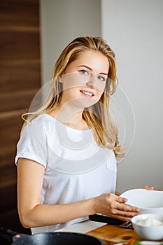 Attractive blonde woman posing at table in her kitchen