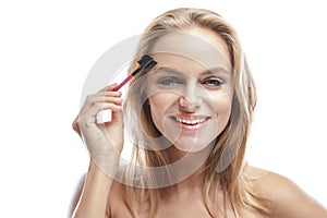 Attractive blonde woman using eyebrows comb