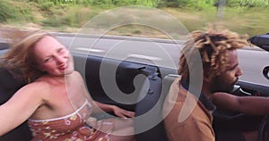 Attractive blonde woman waving her arms to music riding in convertible car