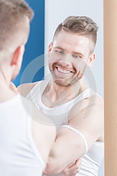 Attractive bodybuilder measuring his biceps