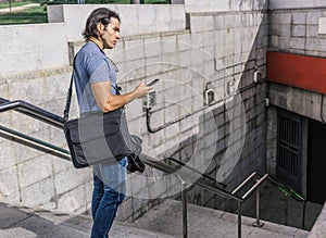 Attractive boy in jeans and blue shirt pensive going down some stairs of a train station