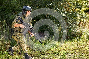 Attractive brave military woman with a gun in forest, survival in wild forest