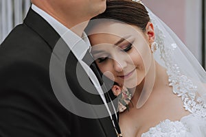 Attractive bride and groom at the ceremony on their wedding day with an arch made of pink and white flowers