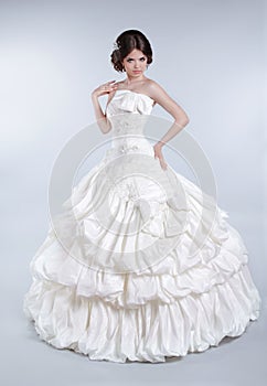 Attractive bride model girl wearing in wedding dress with voluminous skirt, studio photo