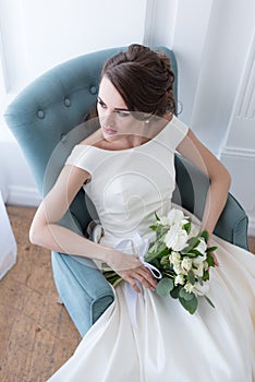 attractive bride with wedding bouquet sitting
