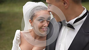 Attractive brunette bride with lovely smile is leaning o nthe shoulder of the groom and looking in his eyes. Close-up