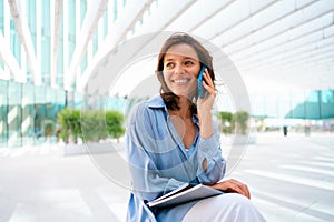 Attractive brunette businesswoman talking mobile phone with client. Pretty caucasian female business person smile when phone