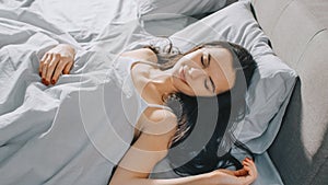 Attractive Brunette Cozily Sleeps in Her Bed while Early Morning Sunrays Illuminate Her. Warm, Coz