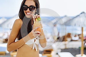 Attractive brunette drinking cocktails on beach