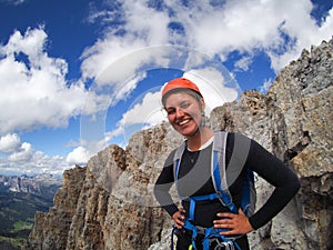 Attractive brunette female climber on a mountain peak in the Dolomites smiling from ear to ear