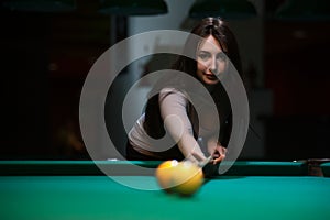 Attractive brunette girl playing billiard game.