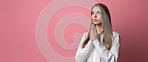 Attractive brunette girl prays for wellness of family  keeps palms pressed together in praying gesture  saying namaste